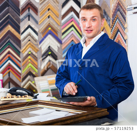 Man worker holding picture frame details on counter 57119253