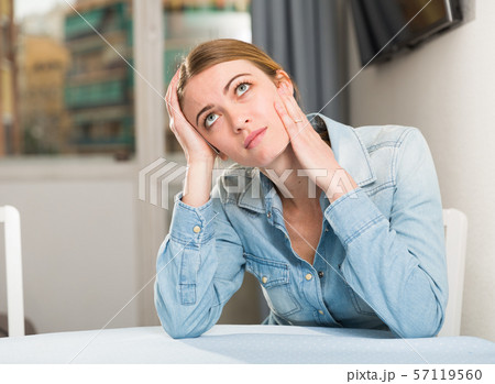 Upset woman sitting at table 57119560