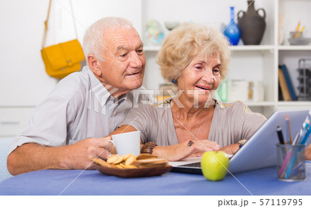 Smiling senior couple surfing net with laptop Smiling senior couple surfing net with laptop 57119795