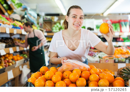 Young female choosing fresh oranges in fruit store 57120265