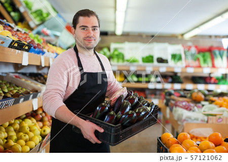 Salesman having tray of eggplants on the supermarket 57121062