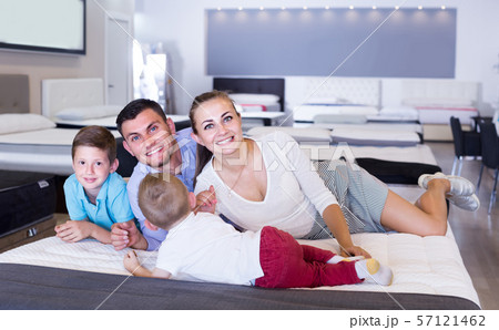 parents with two young sons testing mattress in store 57121462