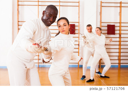 Female fencer practicing movements with african american male trainer Female fencer practicing movements with african american male trainer 57121706