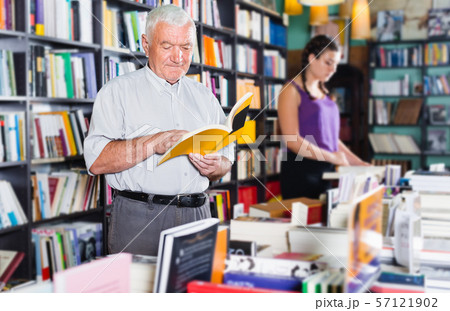 Male 61-67 years old is choosing book for reading in free time 57121902