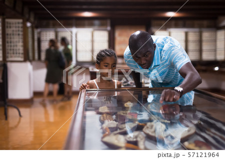 Man and his daughter looking at showcase with exhibits 57121964