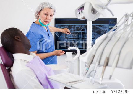 Doctor woman dentist shows patient an x-ray Doctor woman dentist shows patient an x-ray 57122192