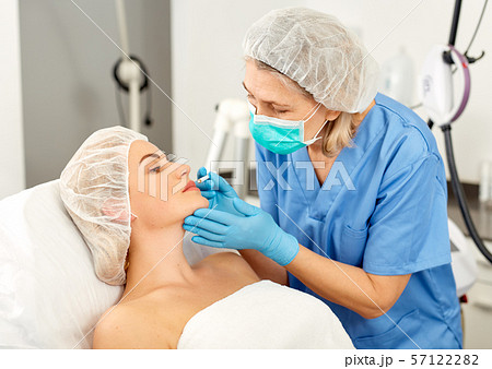 Plastic surgeon preparing for operation on woman face Plastic surgeon preparing for operation on woman face 57122282