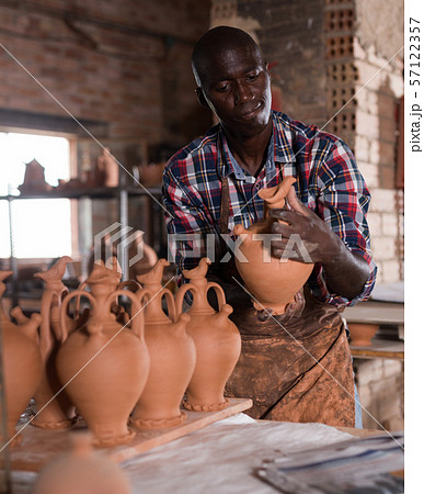 Potter checking quality of ceramic objects Potter checking quality of ceramic objects 57122357
