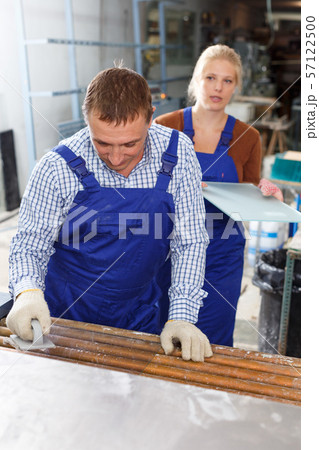 Man and female colleague cleaning glass on washing machine Man and female colleague cleaning glass on washing machine 57122500