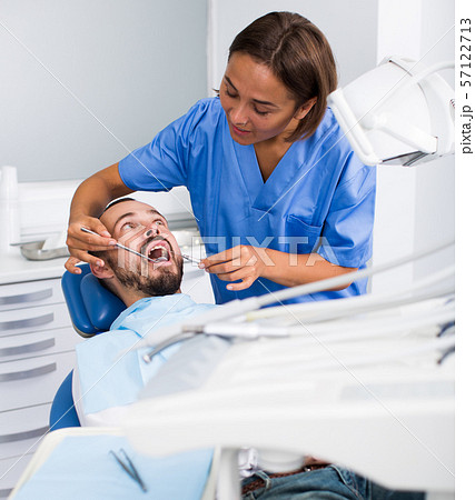 Stomatologist girl in uniform is taking visional inspection of a man in hospital 57122713