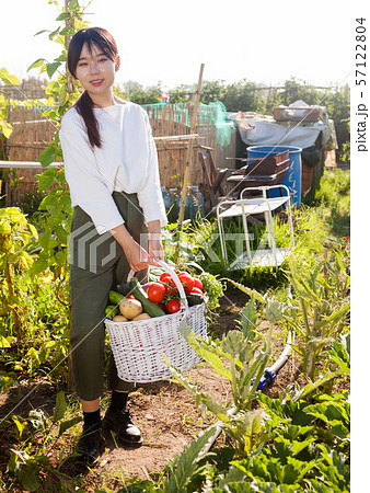Woman holding basket full of vegetables Woman holding basket full of vegetables 57122804