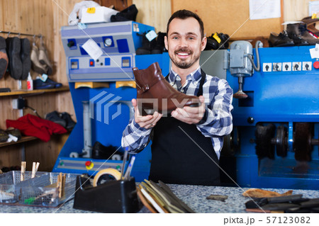 Male worker demonstrating repaired shoes in shoe 57123082