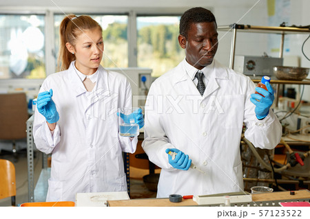 Focused lab technicians in gloves working with reagents and test tubes Focused lab technicians in gloves working with reagents and test tubes 57123522