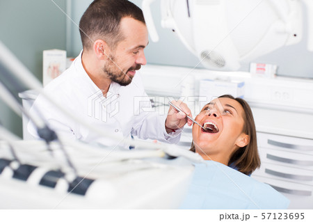 Dentist is treating patient which is sitting in dental chair in clinic Dentist is treating patient which is sitting in dental chair in clinic 57123695