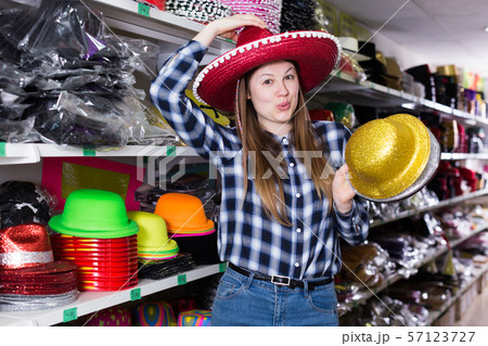 Woman choosing funny headdresses in store 57123727