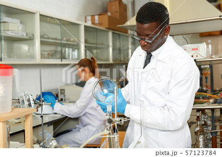 Serious man lab scientist in glasses working with reagents and test tubes Serious man lab scientist in glasses working with reagents and test tubes 57123784