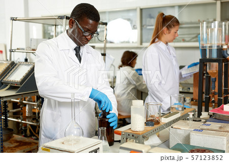 Focused man lab technician in glasses working with reagents and test tubes Focused man lab technician in glasses working with reagents and test tubes 57123852