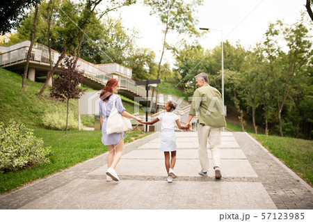 Parents walking with adopted girl hand in hand Parents walking with adopted girl hand in hand 57123985