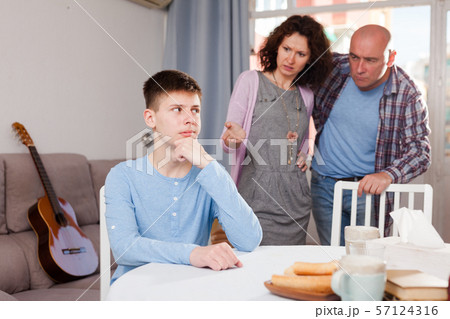 Offended teenager listening to reprimanding from parents Offended teenager listening to reprimanding from parents 57124316