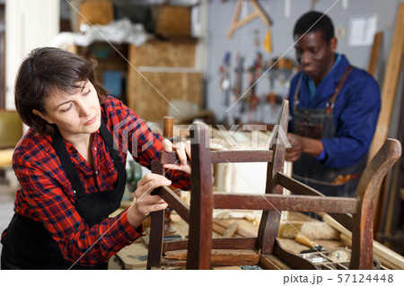 Woman artisan inspecting old chair Woman artisan inspecting old chair 57124448