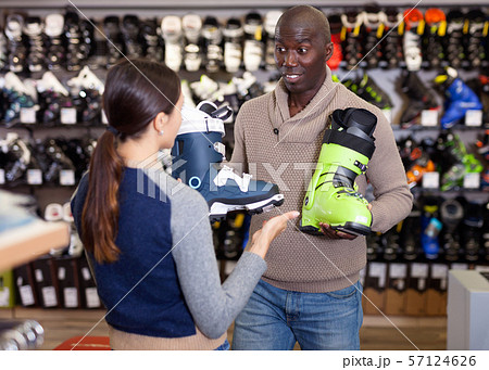 Young African American man with his girlfriend choosing new ski boots in ski equipment shop 57124626