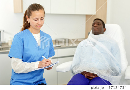 Cosmetician female signing papers before aesthetic facial procedure with man 57124734