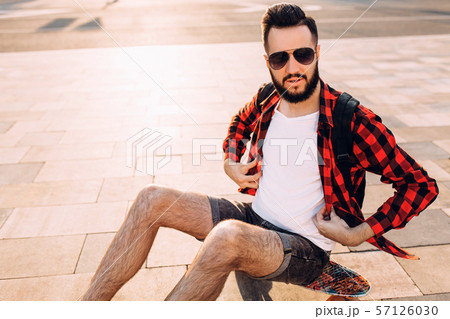 guy with a beard with a skateboard at sunset. guy with a beard with a skateboard at sunset. 57126030