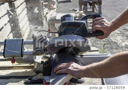 A carpenter saws off a board with a circular saw A carpenter saws off a board with a circular saw 57126059
