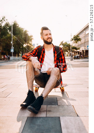 guy with a beard with a skateboard at sunset. 57126215