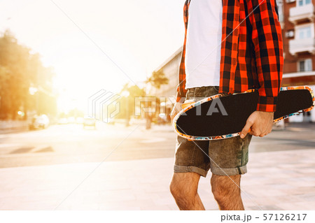 guy with a beard with a skateboard at sunset. 57126217