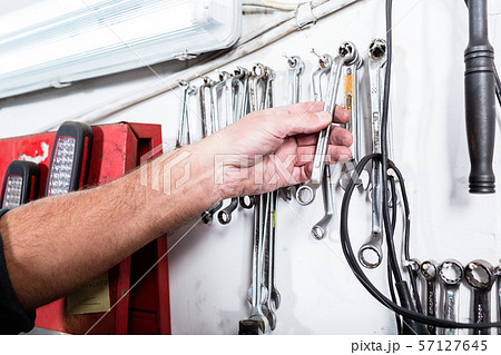 Auto mechanic taking spanner from the wall 57127645