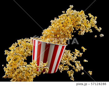 Flying popcorn from striped bucket isolated on black background Flying popcorn from striped bucket isolated on black background 57128286