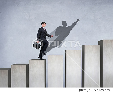 Businessman rise up on the career ladder with superhero shadow on the wall. 57129779