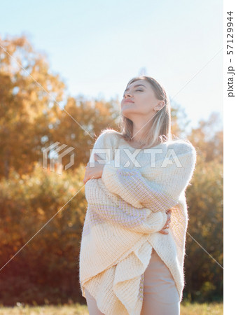Smiling young girl hugging herself and enjoying nature. 57129944