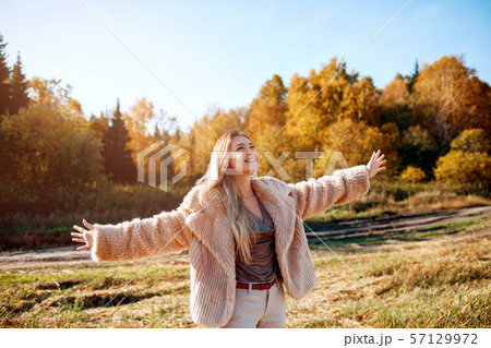 Cheerful girl with raised hands on the field in warm autumn season. Cheerful girl with raised hands on the field in warm autumn season. 57129972