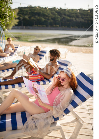 Top view of two women and two men sunbathing and chilling Top view of two women and two men sunbathing and chilling 57130625