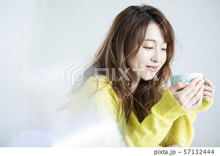 女性 ニット セーター コーヒーカップ マグカップ ホットドリンクの写真素材