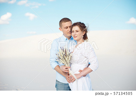 Young man and woman hugging on a background of white sand, dunes. Love story in the void. Young man and woman hugging on a background of white sand, dunes. Love story in the void. 57134505