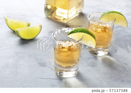 Golden tequila shots with lime slices, salt, a bottle, and a place for text 57137386