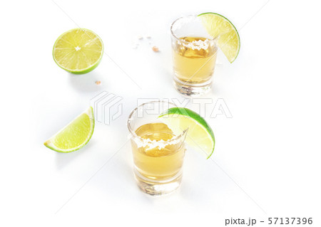 Golden tequila shots with lime slices and salty rims on white with copyspace 57137396