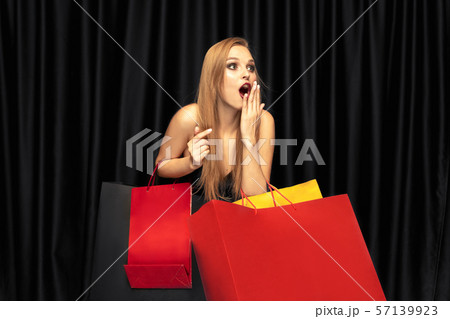 Young woman in dress shopping on black background Young woman in dress shopping on black background 57139923