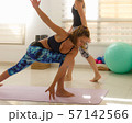 Yoga student entering parivrtta parsvakonasana in bright studio. Young girl in revolved side angle pose. Intense twist, pilates ball, props, colorful sport wear, balance concepts 57142566