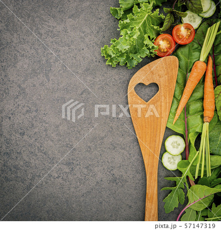 Wooden spoon and vegetables on dark stone Wooden spoon and vegetables on dark stone 57147319