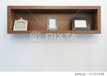 Empty photo frame on wooden shelf with white wall 57153308