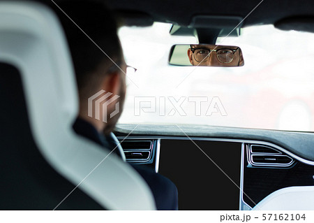 Handsome man wearing glasses looking into rear view mirror Handsome man wearing glasses looking into rear view mirror 57162104