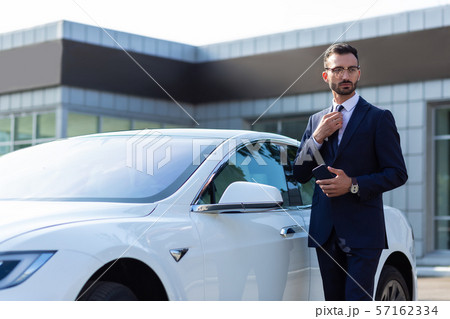 Businessman standing near white car in the morning 57162334