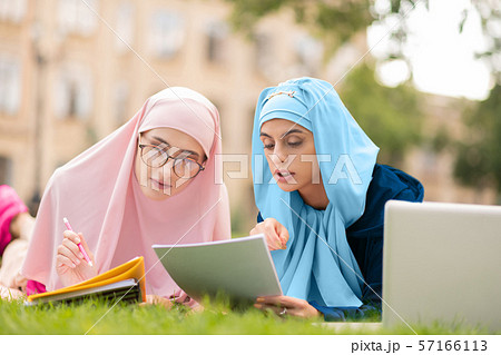Two muslim students in hijab chilling on lane and reading 57166113