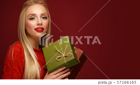 Beautiful blonde girl in a New Year's image with boxes of gifts in hands. Beauty face with festive 57166165