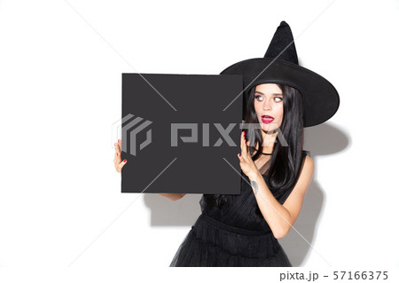 Young woman in hat and dress as a witch on white background 57166375