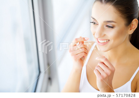 Beautiful young woman teeth close up with copy space on the right side. Isolated over green 57170828